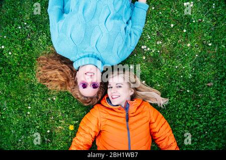 Portrait von zwei glücklichen Freunden, die auf einer Wiese liegen Stockfoto