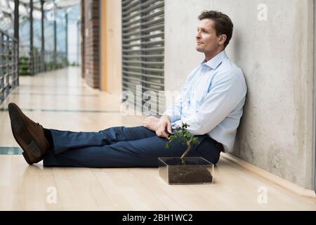 Geschäftsmann im grünen Atrium, auf der Galerie sitzend Stockfoto