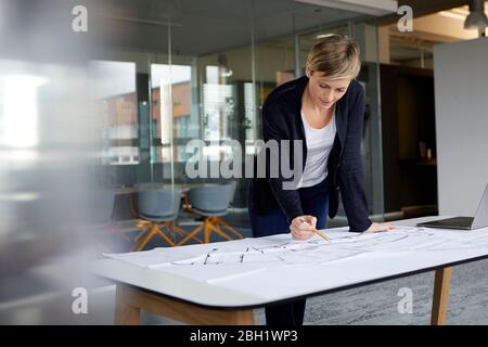 Frau, die im Büro an einem Bauplan arbeitet Stockfoto