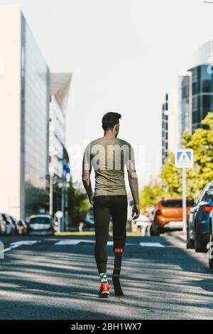 Rückansicht des behinderten Athleten mit Beinprothese auf einer Straße in der Stadt Stockfoto