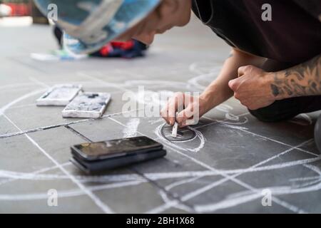 Street Art, Künstler zeichnen ein Auge auf Bürgersteig und mit Smartphone Stockfoto