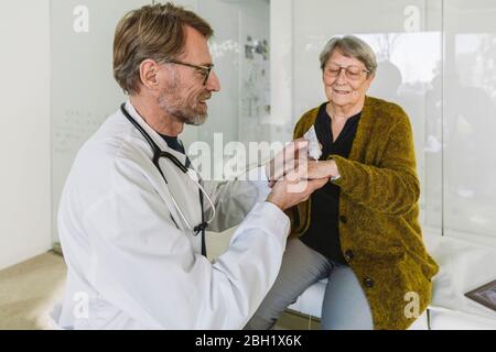 Arzt, der Salbe auf die Hand des älteren Patienten legt Stockfoto