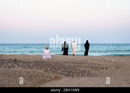 Omanische Männer und Frauen in traditioneller Kleidung am Strand, Qantab, Oman Stockfoto