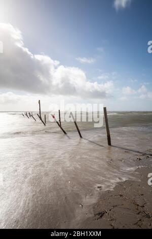 Dänemark, Romo, Blavand, lange Wolkenbelastung über Reihe von Küstenpolen Stockfoto