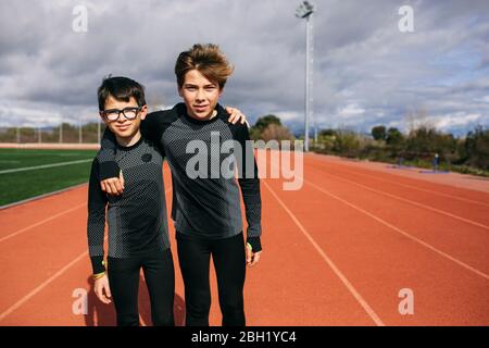 Jungs stehen auf Laufstrecke, mit den Armen um Stockfoto