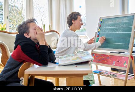 Mutter zu Hause Schulbildung ihr gelangweilter Sohn Stockfoto