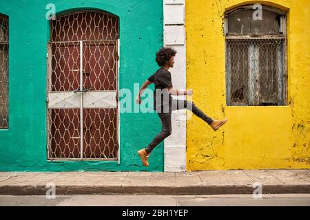 Glücklicher junger Mann, der in der Stadt in der Luft springt Stockfoto