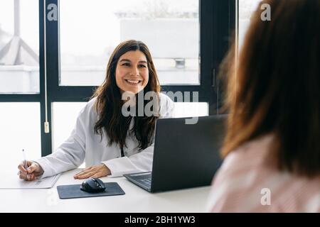 Lächelnd Arzt im Gespräch mit Patienten in der medizinischen Praxis Stockfoto