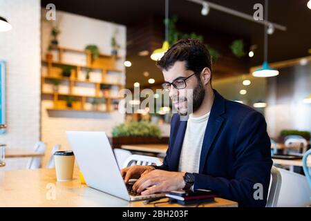 Porträt eines Geschäftsmannes, der in einem Café am Laptop arbeitet Stockfoto