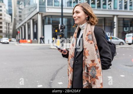 Frau in der Stadt, die die Straße überquert, London, Großbritannien Stockfoto