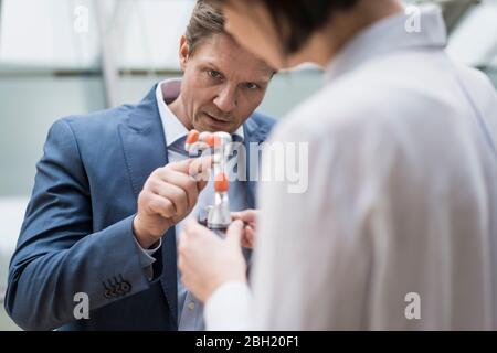 Geschäftsmann und Frau stehen im Atrium des Bürogebäudes, reden über Roboterarm Stockfoto