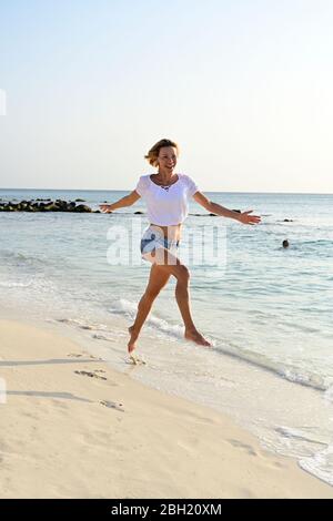 Schöne Frau läuft und springt vor Freude am Strand Stockfoto