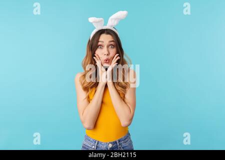 Porträt der jungen glücklichen Frau trägt Spielzeug Häschen Ohren Spaß und zum Ausdruck bringen Überraschung isoliert über blauen Hintergrund im Studio Stockfoto