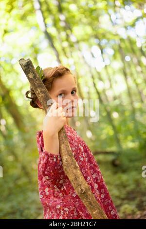 Portrait von Mädchen mit Holzstock zu Fuß im Wald Stockfoto