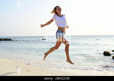 Schöne Frau läuft und springt vor Freude am Strand Stockfoto