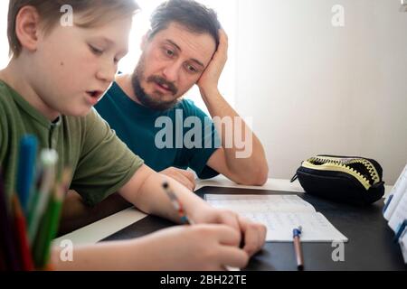 Porträt des Vaters, der seinen Sohn bei den Hausaufgaben beobachtet Stockfoto