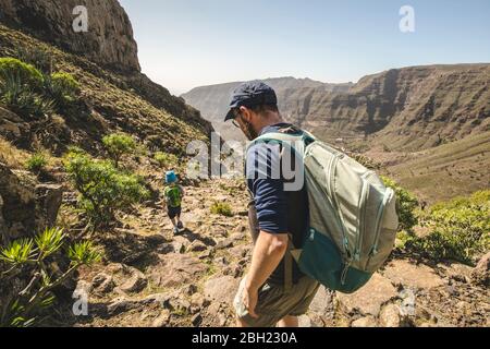 Vater und kleiner Sohn mit Rucksäcken auf einem Wanderweg in den Bergen, La Gomera, Kanarische Inseln, Spanien Stockfoto