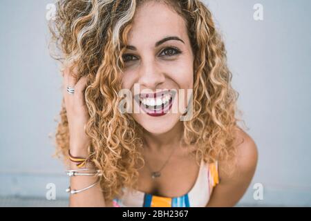 Porträt der glückliche junge Frau mit blonden Korkenzieherlocken Stockfoto