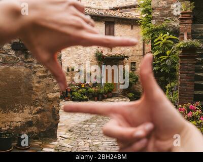 Frau Finger umrahmt ein Haus in der malerischen Altstadt, Greve in Chianti, Toskana, Italien Stockfoto