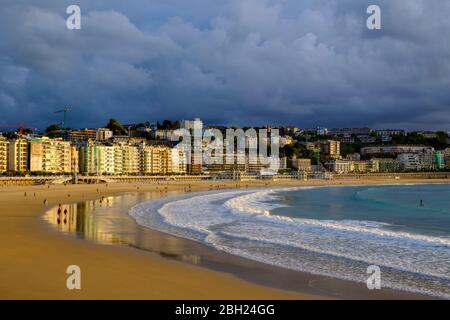 Spanien, Gipuzkoa, San Sebastian, Sturmwolken über Sandstrand der Bucht von La Concha mit Stadtgebäuden im Hintergrund Stockfoto