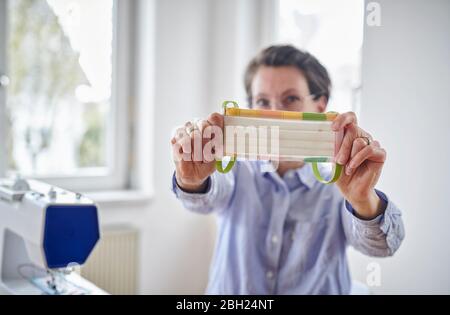 Frau zeigt Gesichtsmaske, hat sie zu Hause genäht Stockfoto