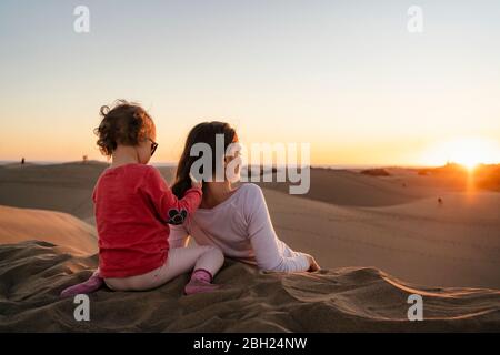 Mutter und Tochter entspannen in Sanddünen bei Sonnenuntergang, Gran Canaria, Spanien Stockfoto