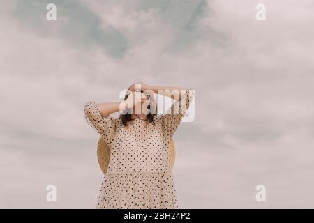 Frau im Vintage-Kleid, das ihre Augen und den Mund bedeckt Stockfoto