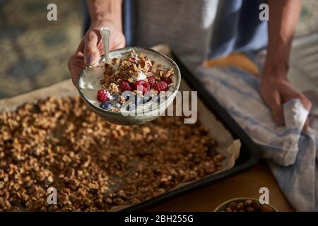 Frau Hand hält Schüssel mit Müsli mit Joghurt und Beeren Stockfoto