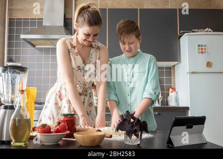 Mutter und Sohn kneten den Teig in der Küche zusammen Stockfoto