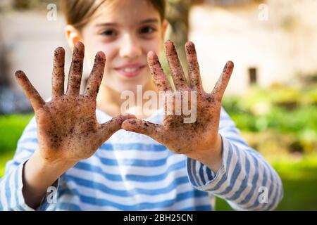 Portrait von lächelndes Mädchen zeigt ihre schmutzigen Hände Stockfoto