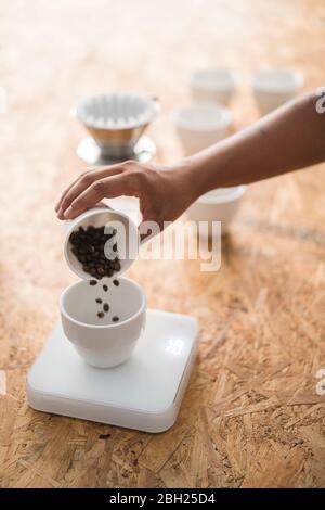 Nahaufnahme einer Frau, die Kaffeebohnen in eine Tasse gießt Stockfoto