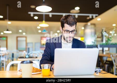 Porträt eines bärtigen Geschäftsmannes, der in einem Café am Laptop arbeitet Stockfoto