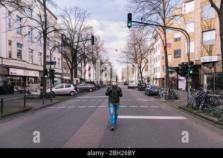 Mann mit Maske, der mitten in einer leeren Straße in der Stadt läuft Stockfoto