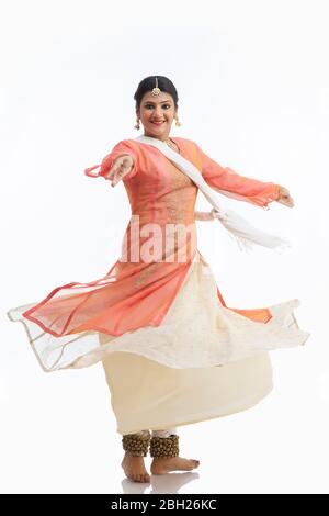 Schöne Kathak Tänzerin kreist vor einem weißen Hintergrund und lächelt. Stockfoto