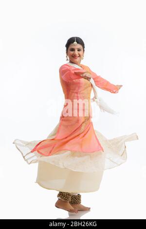 Schöne Kathak Tänzerin kreist vor einem weißen Hintergrund und lächelt. Stockfoto