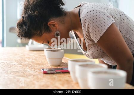 Frau, die in einer Kaffeerösterei arbeitet, die an einem Produkt riecht Stockfoto