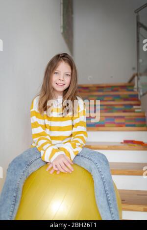 Portrait von glücklichen Mädchen auf Fitness-Ball zu Hause sitzen Stockfoto