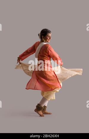 Wunderschöne Kathak Tänzerin kreist vor einem schlichten Hintergrund. Stockfoto