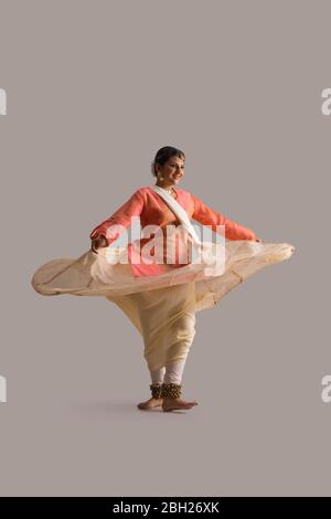 Wunderschöne Kathak Tänzerin kreist vor einem schlichten Hintergrund und lächelt. Stockfoto