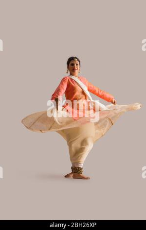 Wunderschöne Kathak Tänzerin kreist vor einem schlichten Hintergrund und lächelt. Stockfoto