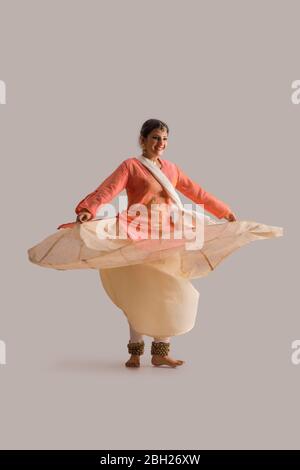 Wunderschöne Kathak Tänzerin kreist vor einem schlichten Hintergrund und lächelt. Stockfoto