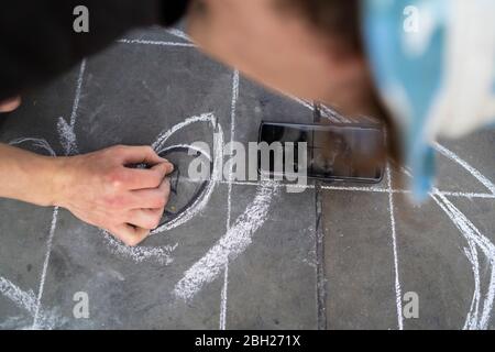 Street Art, Künstler zeichnen ein Auge auf Bürgersteig und mit Smartphone Stockfoto