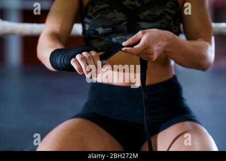 Nahaufnahme einer jungen Frau, die im Boxclub einen Verband um ihre Hand bindet Stockfoto