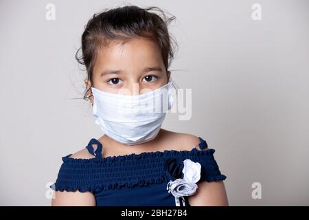 Mädchen Kind Gesicht mit Maske zu Hause bedeckt, um vor der Ausbreitung von Corona-Virus-Infektion zu verhindern. Stockfoto