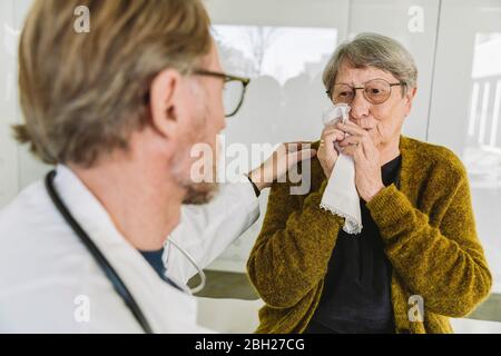 Arzt tröstet traurigen älteren Patienten in der medizinischen Praxis Stockfoto