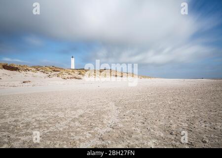 Dänemark, Romo, Blavand, Wolken über Sandstrand mit Leuchtturm im Hintergrund Stockfoto