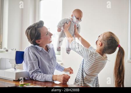 Das kleine Mädchen und ihre Puppe, die Gesichtsmasken trägt, hat ihre Mutter für sie gemacht Stockfoto