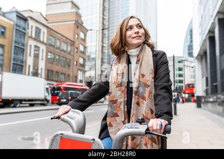 Frau in der Stadt mit Leihrad, London, Großbritannien Stockfoto