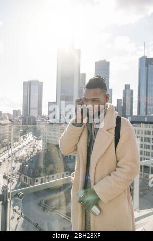 Stilvoller Mann am Telefon auf Aussichtsterrasse mit skycraper-Blick, Frankfurt, Deutschland Stockfoto