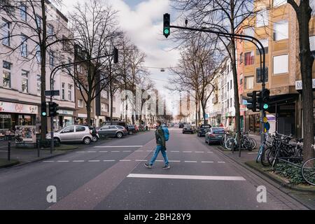 Mann mit Maske, der mitten in einer leeren Straße in der Stadt läuft Stockfoto